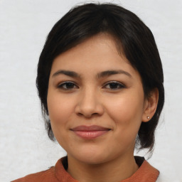 Joyful latino young-adult female with medium  brown hair and brown eyes