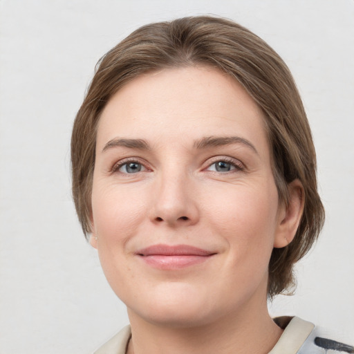 Joyful white young-adult female with medium  brown hair and grey eyes