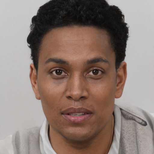 Joyful black young-adult male with short  brown hair and brown eyes