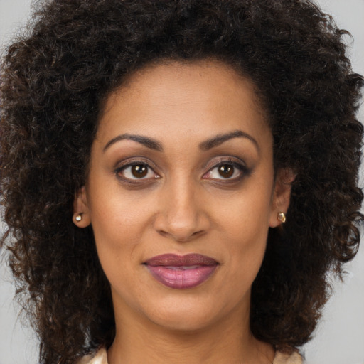 Joyful black young-adult female with long  brown hair and brown eyes