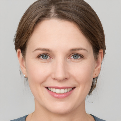 Joyful white young-adult female with medium  brown hair and grey eyes