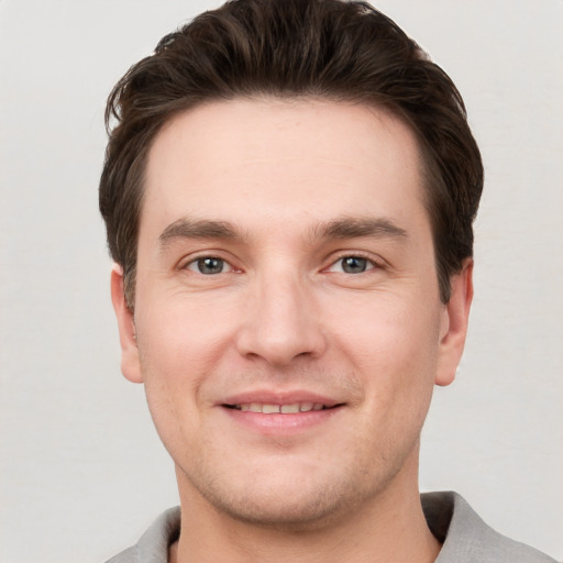 Joyful white young-adult male with short  brown hair and grey eyes