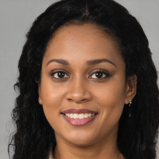 Joyful black young-adult female with long  black hair and brown eyes
