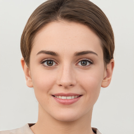 Joyful white young-adult female with short  brown hair and grey eyes