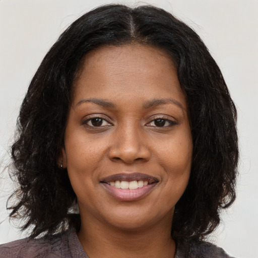 Joyful black young-adult female with long  brown hair and brown eyes