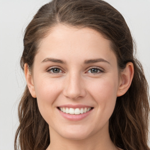 Joyful white young-adult female with long  brown hair and grey eyes