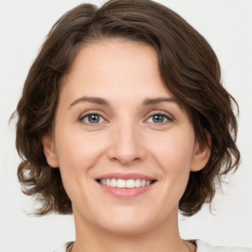 Joyful white young-adult female with medium  brown hair and green eyes