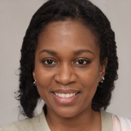 Joyful black young-adult female with long  brown hair and brown eyes