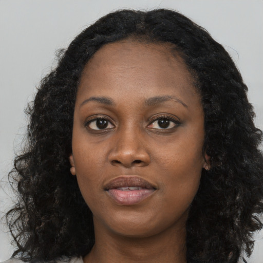 Joyful black young-adult female with long  black hair and brown eyes