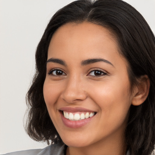 Joyful latino young-adult female with long  brown hair and brown eyes