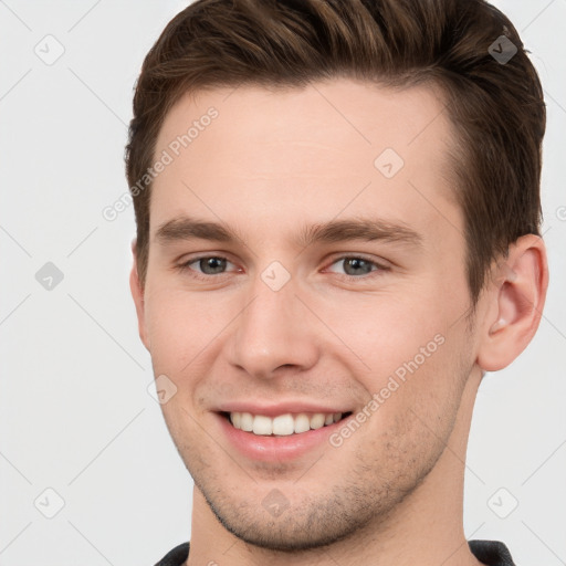 Joyful white young-adult male with short  brown hair and grey eyes