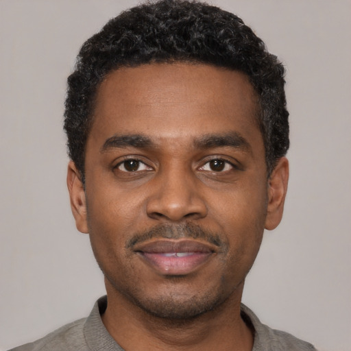 Joyful black young-adult male with short  black hair and brown eyes