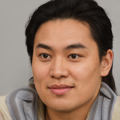 Joyful asian young-adult male with long  brown hair and brown eyes