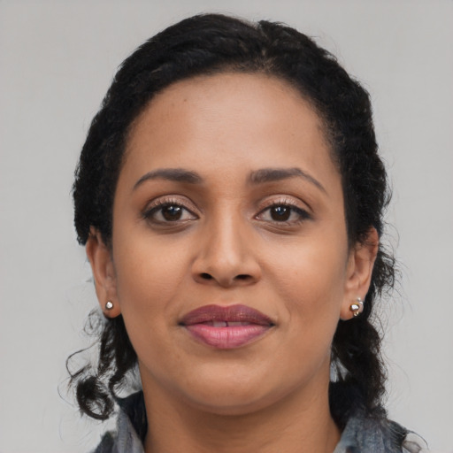 Joyful black young-adult female with long  black hair and brown eyes