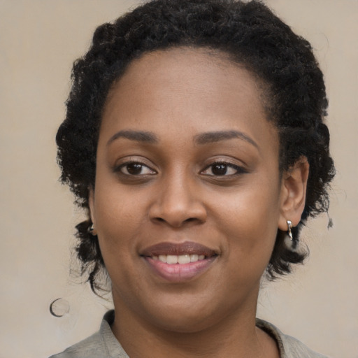 Joyful black young-adult female with long  black hair and brown eyes
