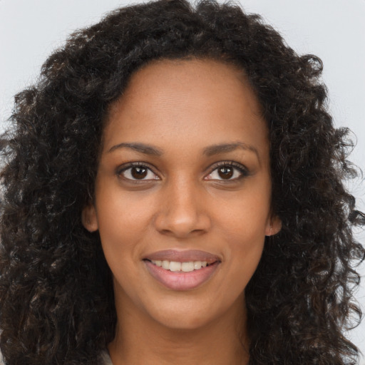 Joyful black young-adult female with long  brown hair and brown eyes