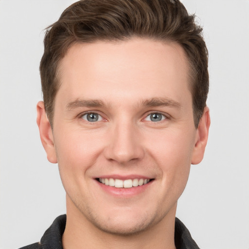 Joyful white young-adult male with short  brown hair and grey eyes