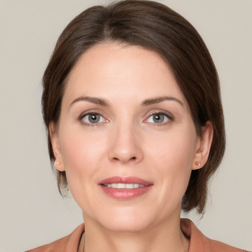 Joyful white young-adult female with medium  brown hair and grey eyes