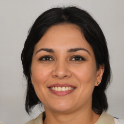 Joyful latino adult female with medium  brown hair and brown eyes