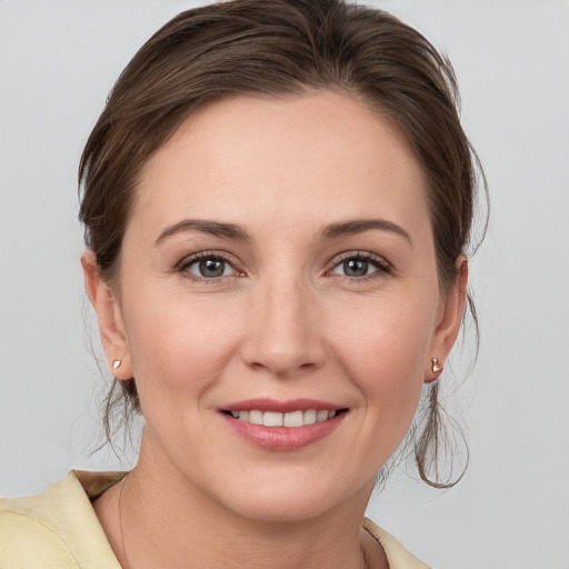 Joyful white young-adult female with medium  brown hair and grey eyes