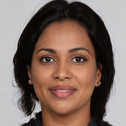 Joyful black young-adult female with long  brown hair and brown eyes
