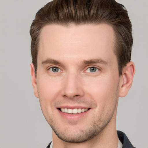 Joyful white young-adult male with short  brown hair and grey eyes