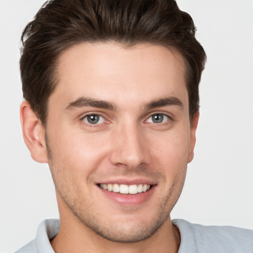 Joyful white young-adult male with short  brown hair and grey eyes