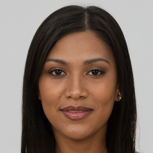 Joyful black young-adult female with long  brown hair and brown eyes