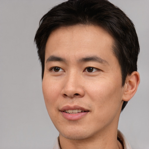 Joyful asian young-adult male with short  brown hair and brown eyes