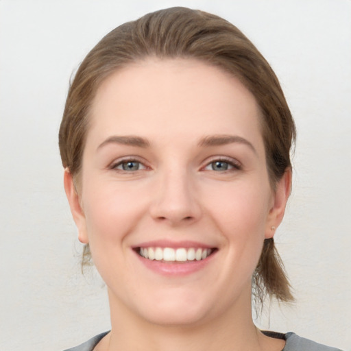 Joyful white young-adult female with medium  brown hair and grey eyes