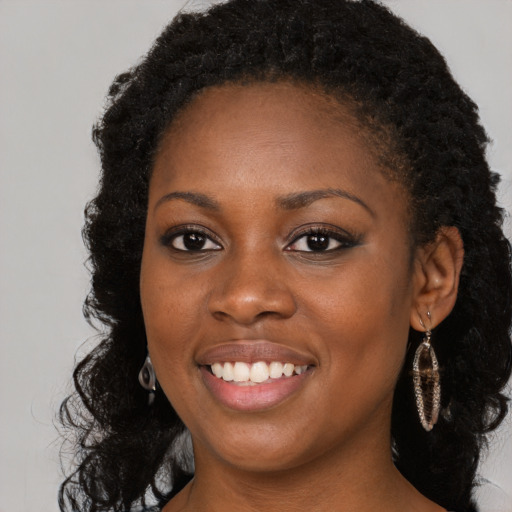 Joyful black young-adult female with long  black hair and brown eyes