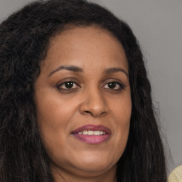 Joyful black young-adult female with long  brown hair and brown eyes