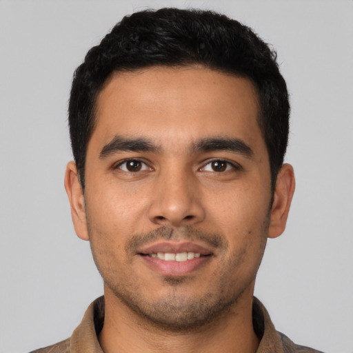 Joyful latino young-adult male with short  black hair and brown eyes