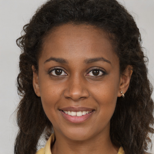 Joyful black young-adult female with long  brown hair and brown eyes