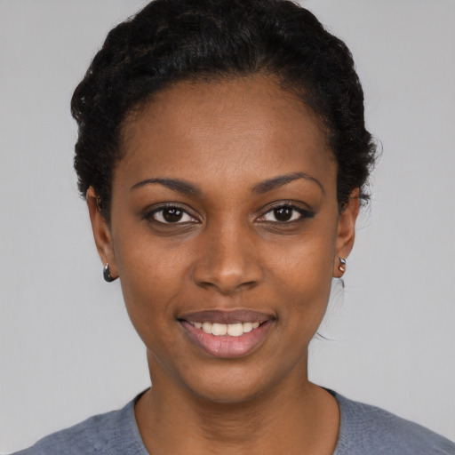 Joyful black young-adult female with short  black hair and brown eyes