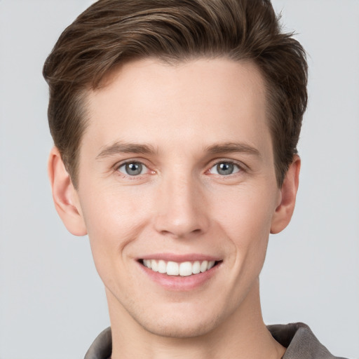 Joyful white young-adult male with short  brown hair and grey eyes