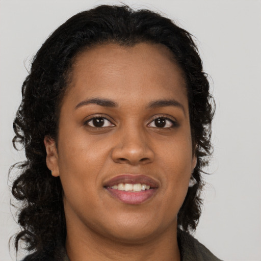 Joyful black young-adult female with long  brown hair and brown eyes