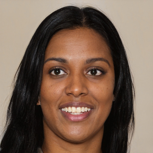Joyful black young-adult female with long  brown hair and brown eyes