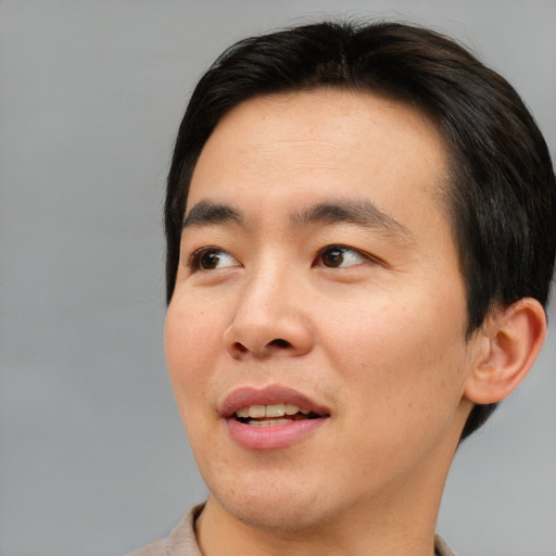 Joyful asian young-adult male with short  brown hair and brown eyes