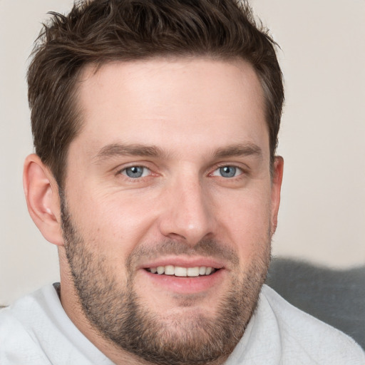 Joyful white young-adult male with short  brown hair and grey eyes