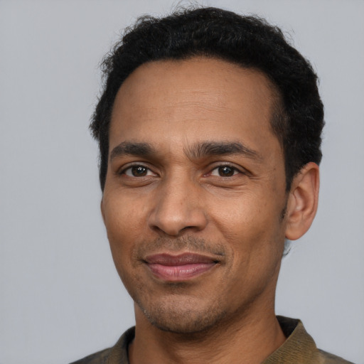 Joyful black adult male with short  black hair and brown eyes