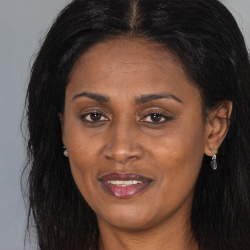 Joyful black adult female with long  brown hair and brown eyes