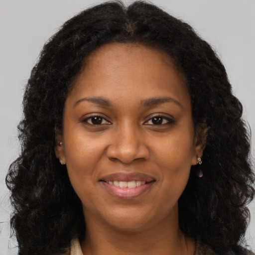 Joyful black young-adult female with long  brown hair and brown eyes