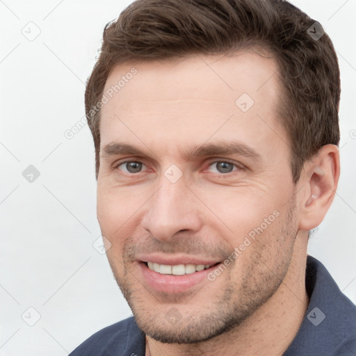 Joyful white young-adult male with short  brown hair and grey eyes