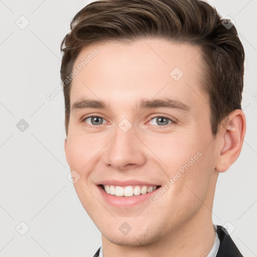 Joyful white young-adult male with short  brown hair and grey eyes