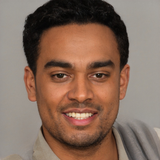 Joyful latino young-adult male with short  black hair and brown eyes