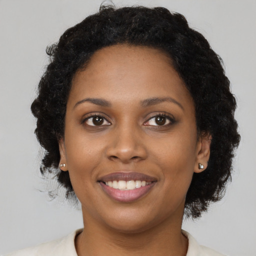 Joyful black young-adult female with short  brown hair and brown eyes