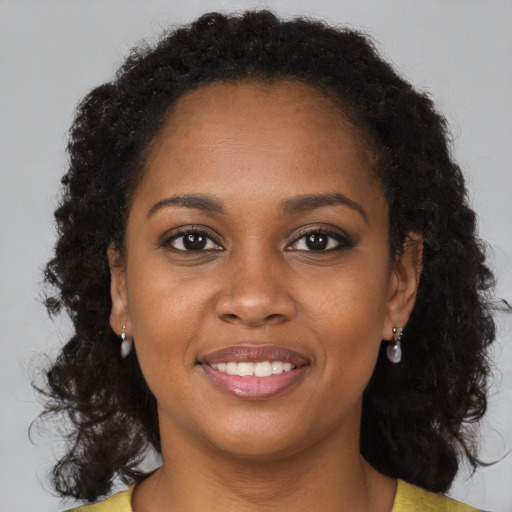 Joyful black young-adult female with long  brown hair and brown eyes