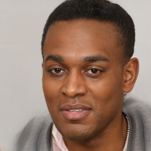 Joyful black young-adult male with short  black hair and brown eyes