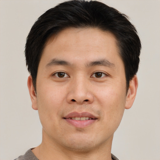 Joyful asian young-adult male with short  brown hair and brown eyes